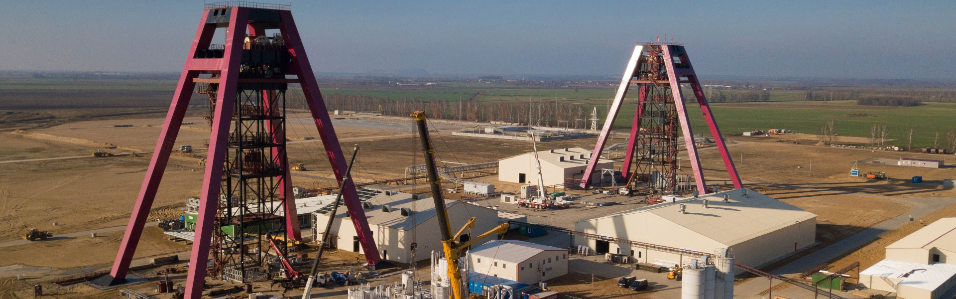 La page de la bannière du site Web Redpath pour l'Europe montre un site minier centré autour de deux hauts cadres de tête rouges sur fond de plaines et de ciel brumeux.