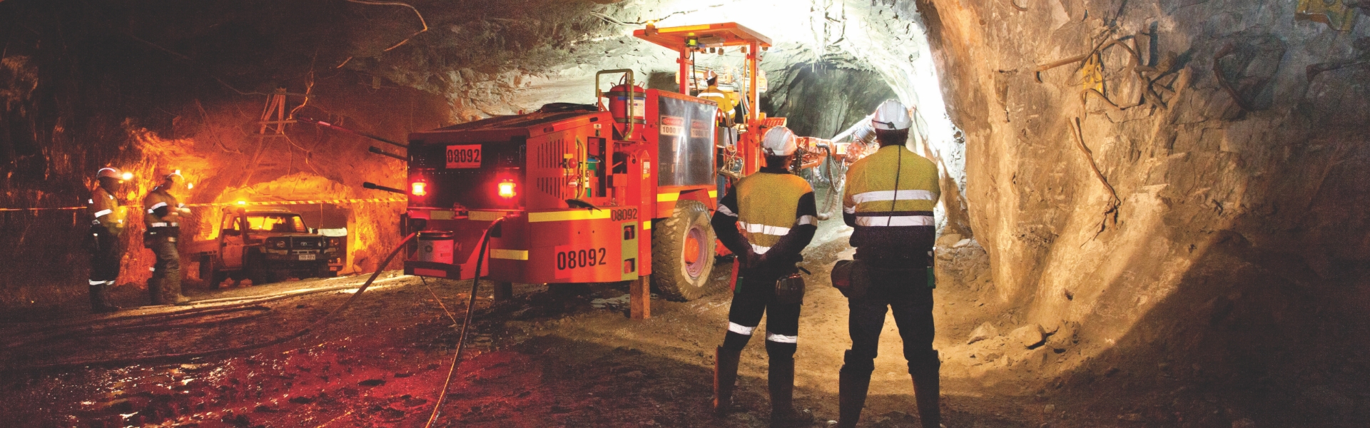 Les employés de Redpath observent une machine jumbo effectuant un forage latéral dans un tunnel souterrain.