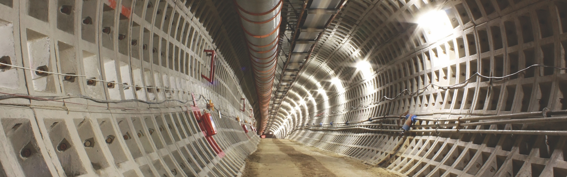 Túnel subterráneo con paredes construidas a partir de un patrón de rectángulos empotrados, dispuestos en forma de cuadrícula que se curva a lo largo del arco del túnel.